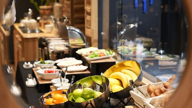 A buffet setup with various food items and a glass display case. - La Suite Boutique Hotel (Tirana)