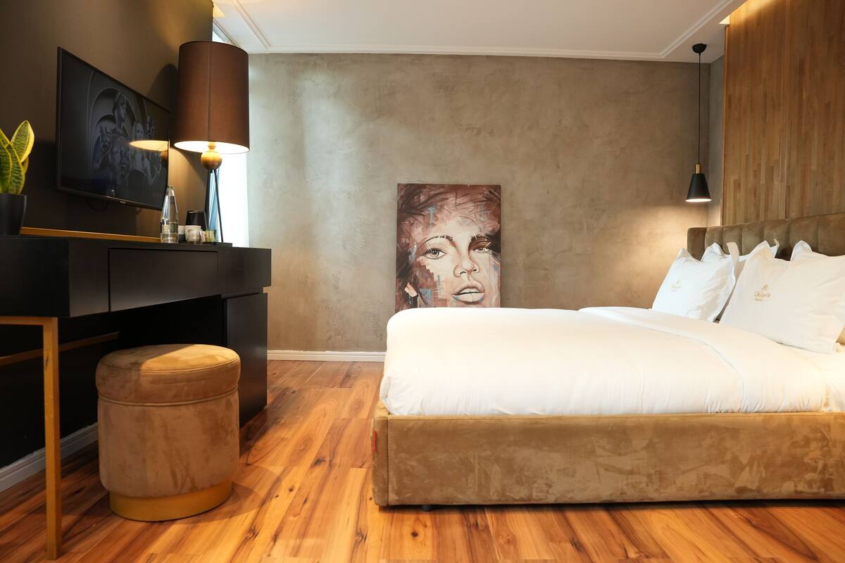Une chambre moderne avec un grand lit, un bureau et un tableau accroché au mur.
