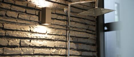 A modern shower with a metal frame and a textured wall behind it.
