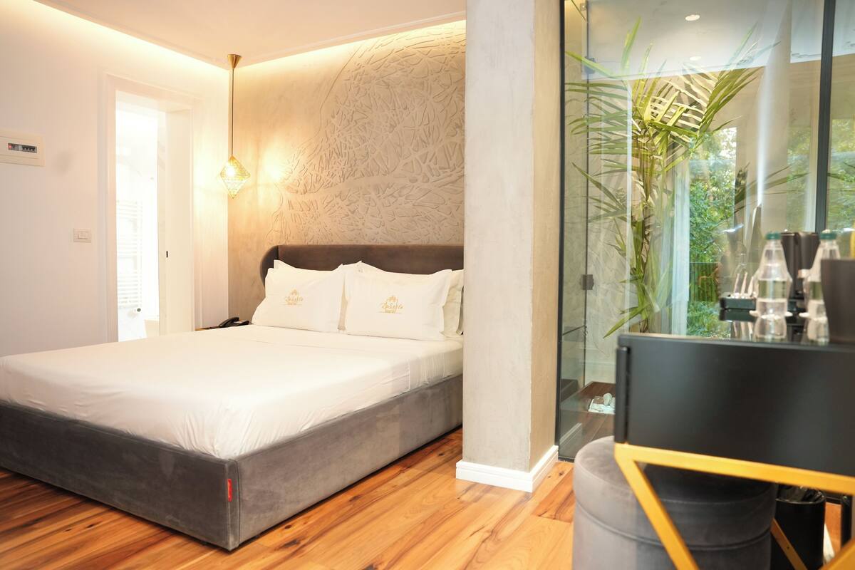 Une chambre moderne avec un grand lit, une cloison en verre et un plancher en bois.