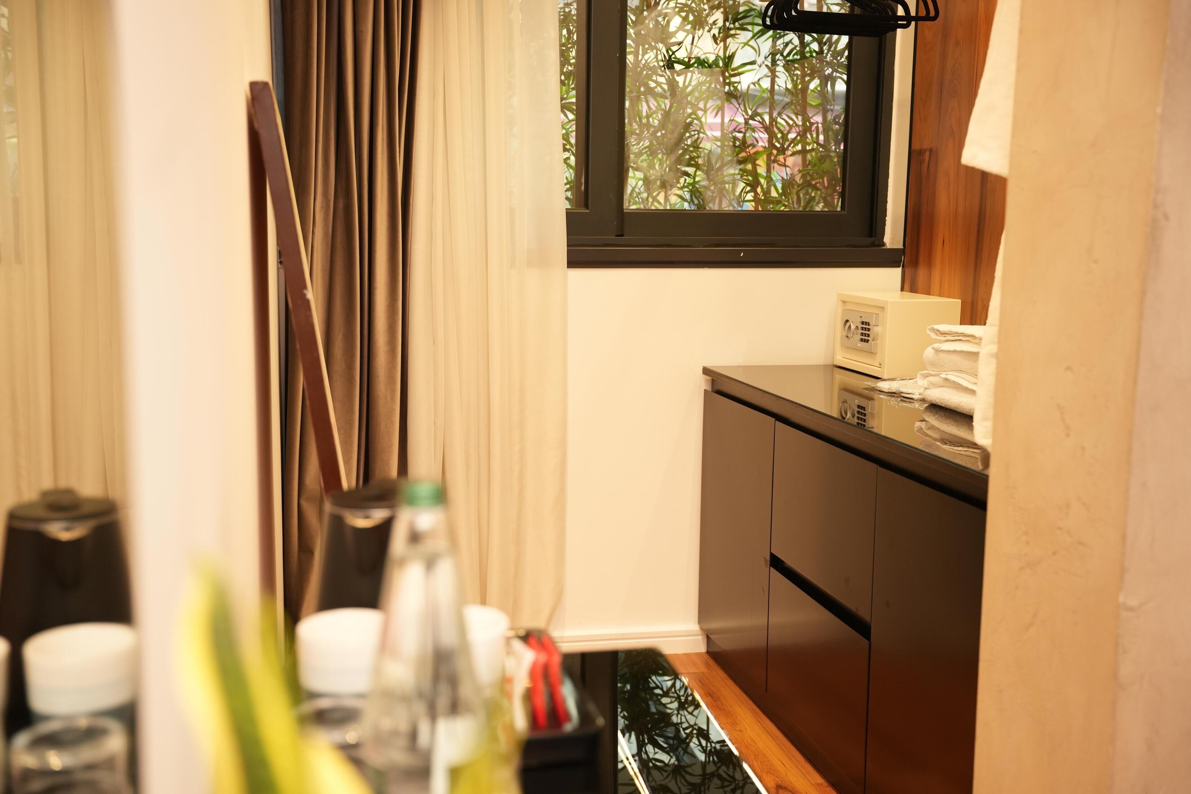Un baño con tocador de madera, una ventana con cortinas y una mesita con artículos de aseo.