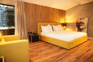 Un dormitorio con una cama grande, paredes de paneles de madera, una mesita de noche, una lámpara y una ventana con cortinas.
