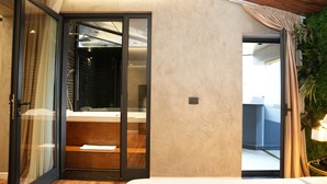 A modern hotel room with a sliding glass door leading to a balcony, a wooden floor, and a large potted plant. - La Suite Boutique Hotel (Tirana)
