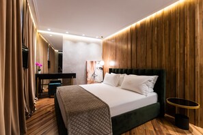 Relax in a spacious room with a large bed, wooden panel wall, and a desk for work.