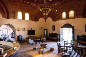 A spacious lobby with a high ceiling, arched windows, and a chandelier. There are several seating areas, a reception desk, and a large mirror on the wall. - Shanda Lodge Desert Resort (Shurtah al-Dakhlah)