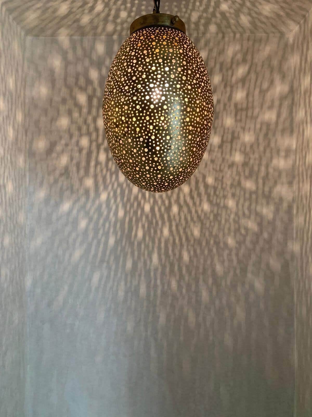 A spherical pendant light with a perforated pattern.