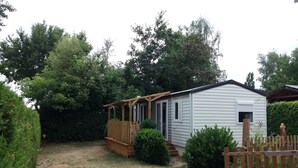 Une petite maison mobile d’un seul étage, dotée d’une véranda et d’une cour clôturée.