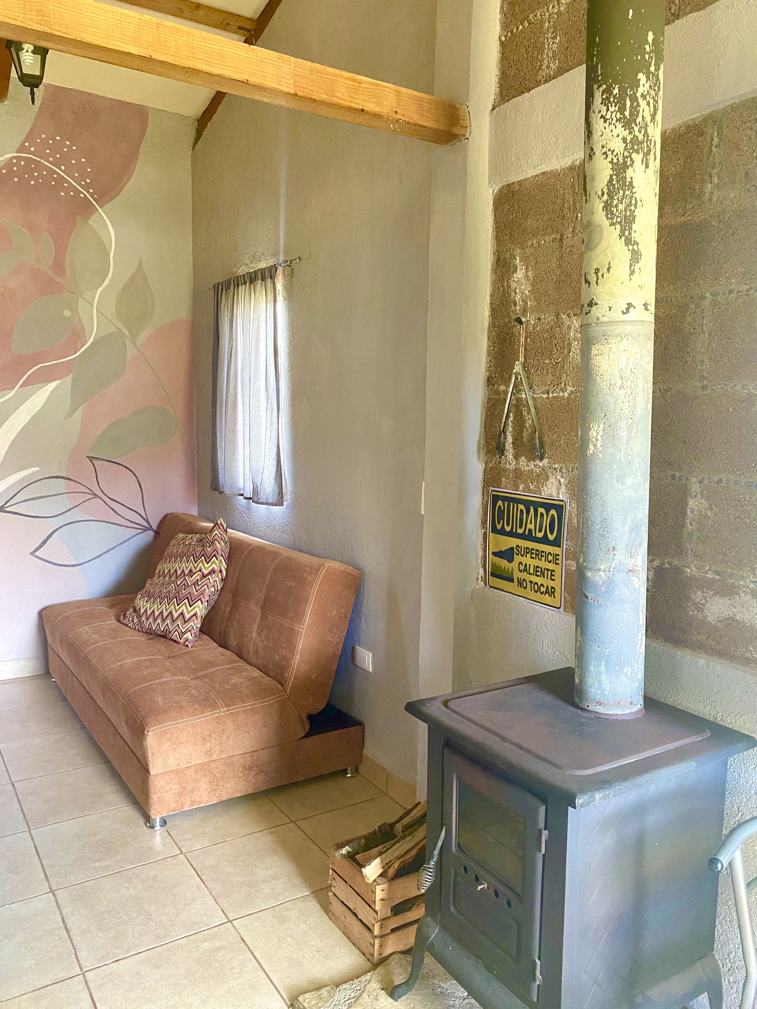 A cozy living room with a sofa, a fireplace, and a caution sign on the wall.