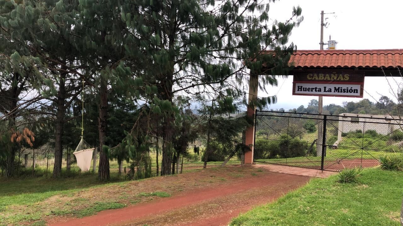 Una entrada protegida por un portón con un letrero que dice "CABANAS Huerta La Misión".