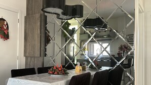 Ein moderner Essbereich mit Glastrennwand, einem Tisch mit weißem Tuch, schwarzen Stühlen und einer Kristallleuchter.