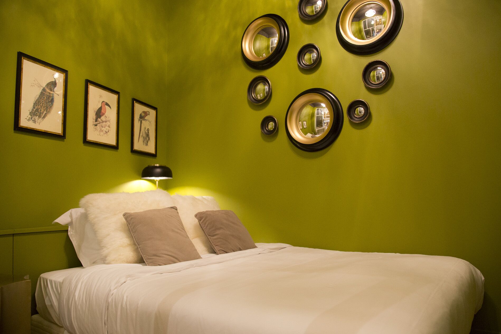 Una habitación con una cama, paredes verdes y cuadros enmarcados.