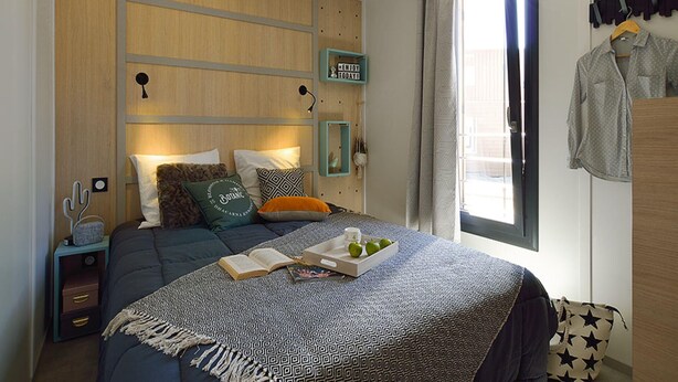 A bedroom with a bed, bedside tables, a window with curtains, and wall decorations.
