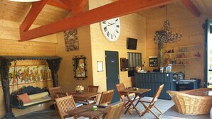 A cozy wooden interior with a dining area, a sofa, and a clock on the wall.