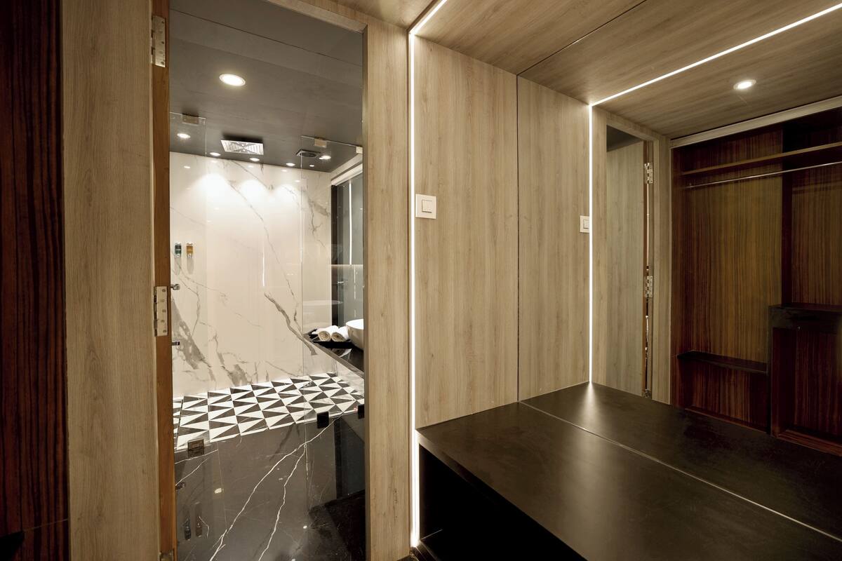 Un baño moderno con tocador de mármol, paneles de madera y salpicadero de azulejos geométricos.
