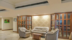 A spacious living area with a beige sofa set, a coffee table, and a decorative wall panel. - Kumar Resort by Turtle, Lonavala (Mawal)