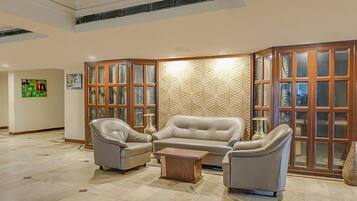 A spacious living area with a beige sofa set, a coffee table, and a decorative wall panel.