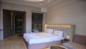 A modern hotel room with a large bed, a bedside table with a phone, and a bathroom with a bathtub. - Kumar Resort by Turtle, Lonavala (Mawal)