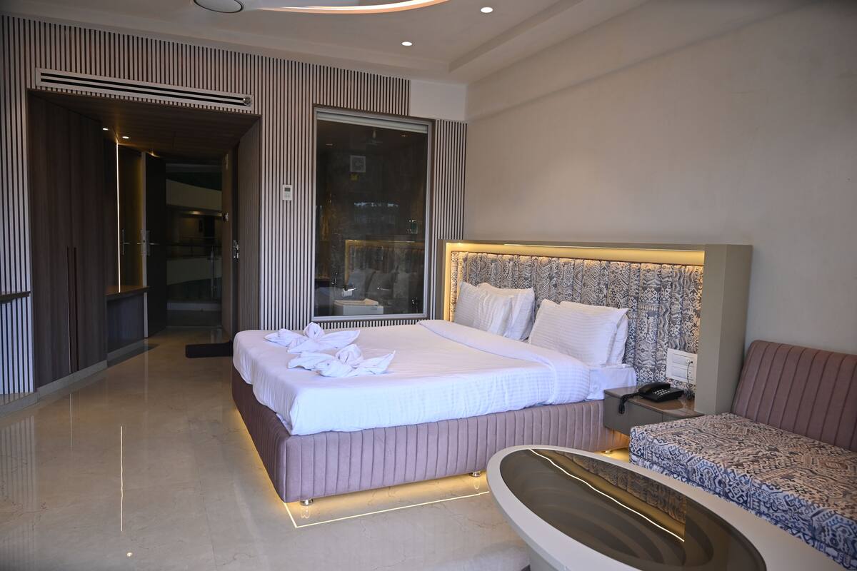 Una habitación de hotel moderna con una cama grande, una mesita de noche con teléfono y un baño con bañera.