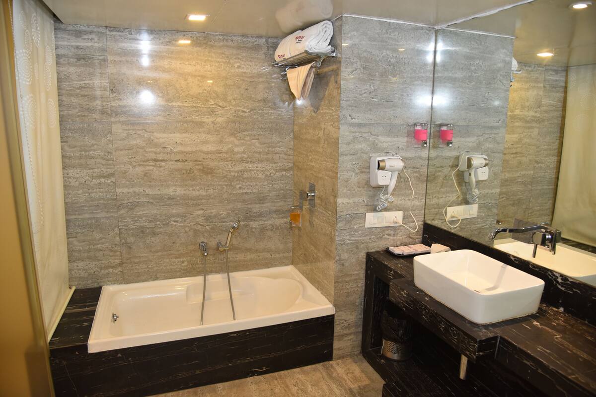 Un baño moderno con una bañera grande, dos lavamanos y un secador de pelo fijado a la pared.