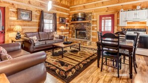 L’intérieur d’un chalet confortable en bois, avec un salon, une cheminée, un coin repas et une cuisine.