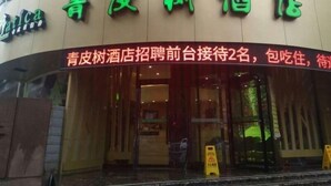 A hotel entrance with a neon sign in green and red. - Vatica Qingdao Licang Xiazhuang Hexie Plaza Hotel (Qingdao)
