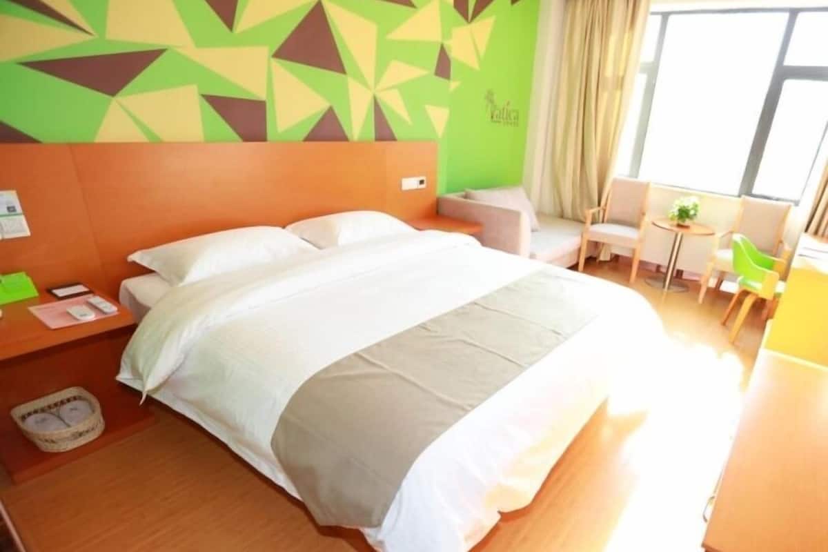 Ein Hotelzimmer mit einem großen Bett, einem kleinen Schreibtisch, einem Sessel und einem Sofa.