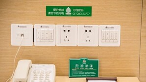 Una habitación de hotel con un teléfono, un control remoto y un lector de tarjetas en el escritorio.
