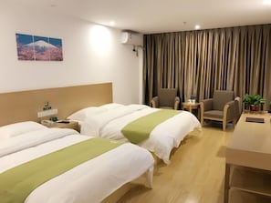 Habitación de hotel con dos camas, un escritorio, una silla, una mesita y aire acondicionado instalado en la pared.