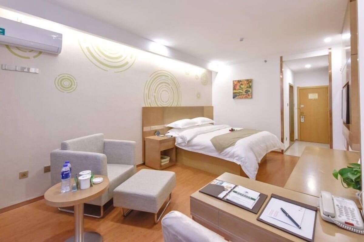 Una habitación de hotel moderna con una cama, un escritorio, una silla, una mesita pequeña y un televisor.