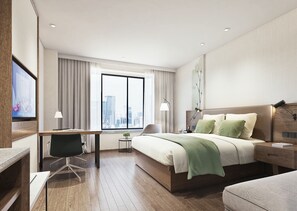 Quarto de hotel moderno com uma cama grande, uma escrivaninha, uma cadeira e vista para a cidade pela janela.