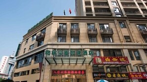 Un hôtel doté d’une façade en verre, de nombreux balcons et d’une enseigne rouge à l’entrée.