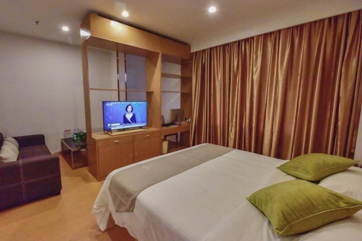 Una habitación de hotel con cama, televisión, escritorio y sofá.