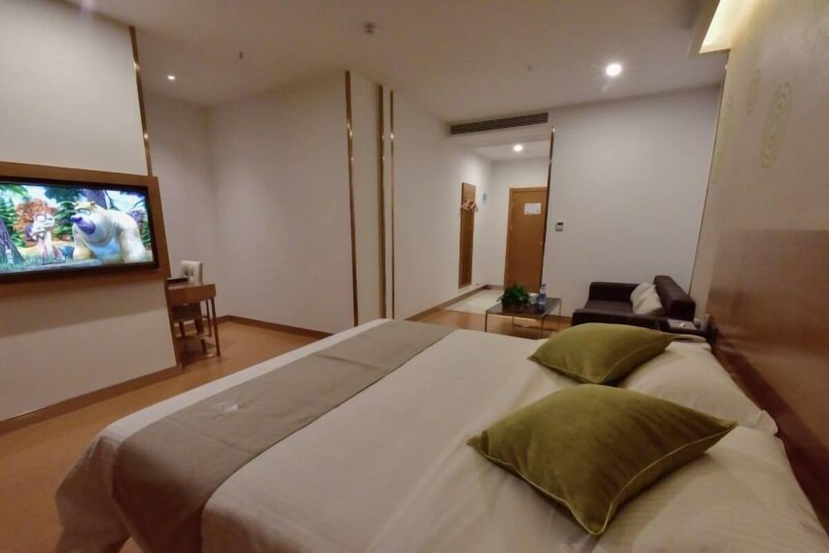 Habitación de hotel con una cama grande, televisión instalada en la pared, un escritorio y una silla.
