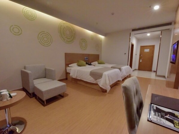 A hotel room with two beds, a sofa, a small table, and a TV.