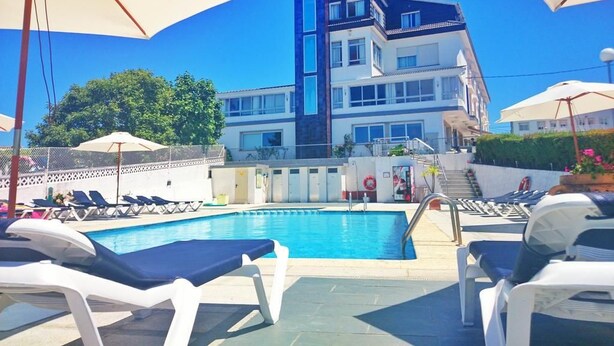 A hotel with a swimming pool, sun loungers, and umbrellas. - Marola (Sanxenxo)