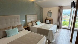 Quarto de hotel com duas camas, uma mesa de cabeceira com abajur, espelho e televisão na parede.