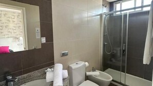 Casa de banho com chuveiro, sanita e lavatório.