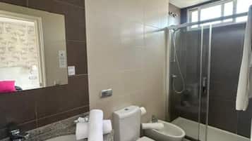 Casa de banho com chuveiro, sanita e lavatório.