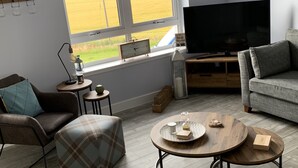 Een moderne woonkamer met een groot raam, een flatscreen televisie en een gezellige zithoek.