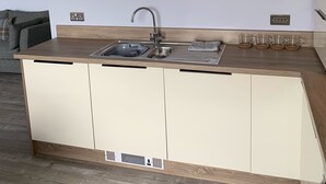 Een moderne keuken met een ingebouwde gootsteen, een houten aanrechtblad en een plank boven de gootsteen met potten en kommen.