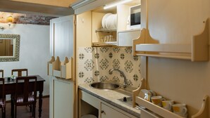 A compact kitchen with a sink, a dining table with chairs, and a mirror. - Apartment Corte Fiorita Historical Center (Lucca)