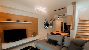 Uma sala de estar moderna com uma televisão de tela plana, um sofá, uma mesa de centro com frutas e uma escada minimalista.