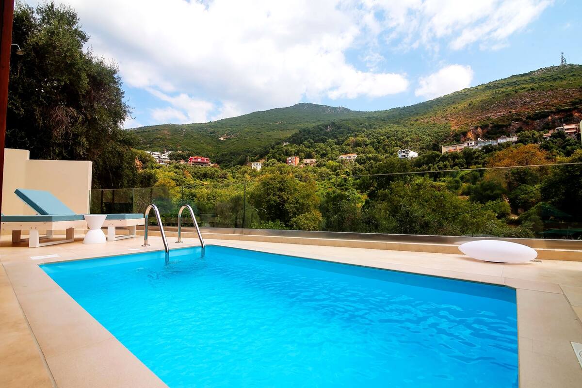 A swimming pool with a view of a hillside and houses.