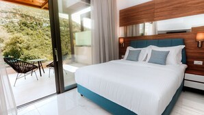 Quarto de hotel moderno com uma cama grande, cabeceira de madeira e varanda com área de estar ao ar livre.