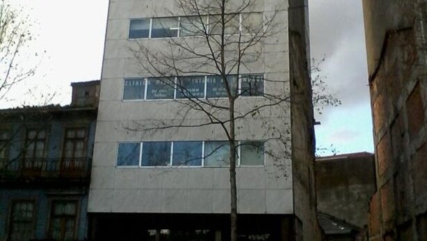A multi-story building with a plain facade, several windows, and a tree in front. - Metro-Apartment - Porto (Porto)