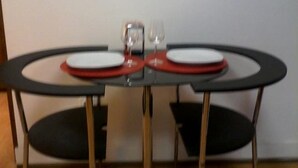A small, round dining table with two chairs, a glass, and a plate. - Metro-Apartment - Porto (Porto)