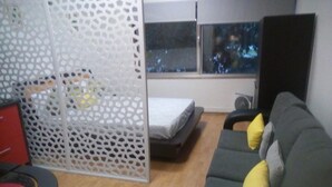 A compact living space with a sofa, a bed, a small table, and a decorative partition. - Metro-Apartment - Porto (Porto)