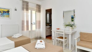 Ein Hotelzimmer mit zwei Betten, einem Schreibtisch, einem Stuhl, einem Spiegel und einer Zimmerpflanze.