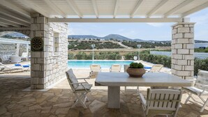 Eine Terrasse im Freien mit Steinpfeilern, einem Tisch und Stühlen mit Blick auf einen Pool und eine Berglandschaft.