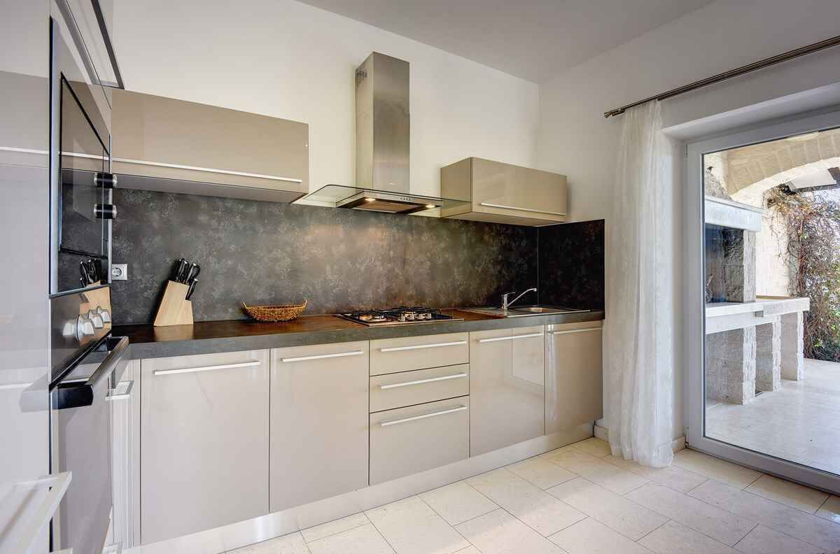 A modern kitchen with a gas stove, stainless steel appliances, and a large window offering a view of the outdoors.